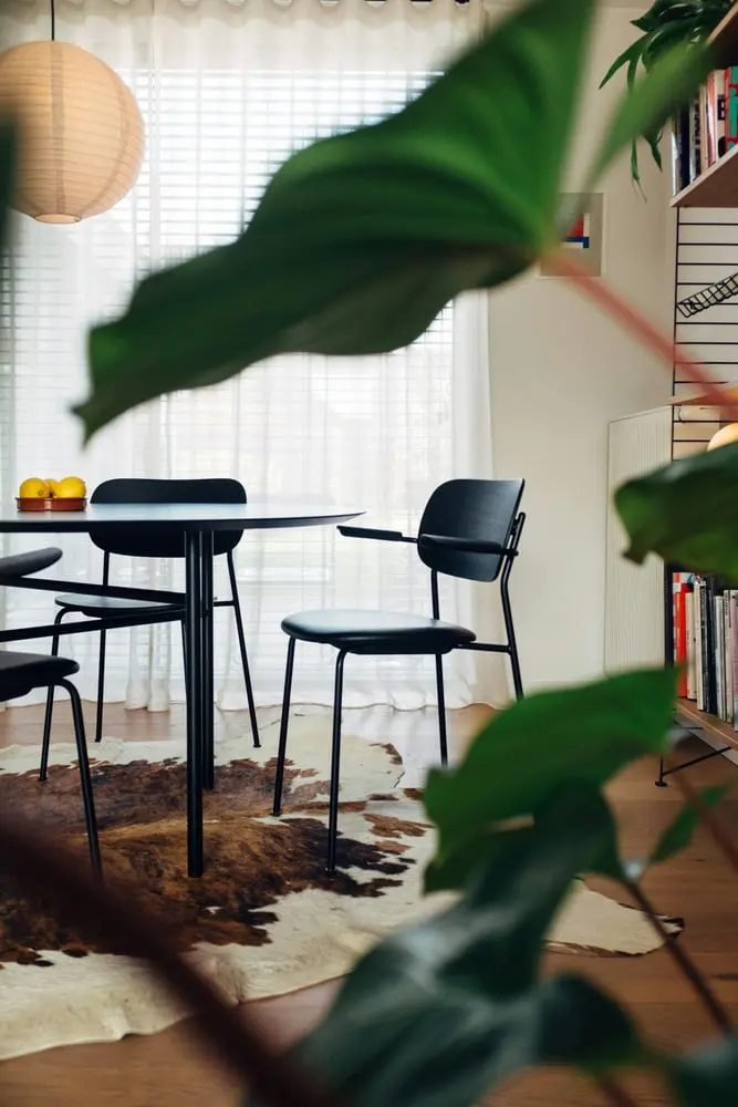 a room with a table chairs and bookshelf