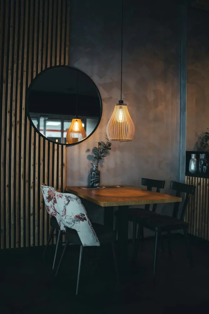 cozy dining nook with a round mirror and hanging lamp