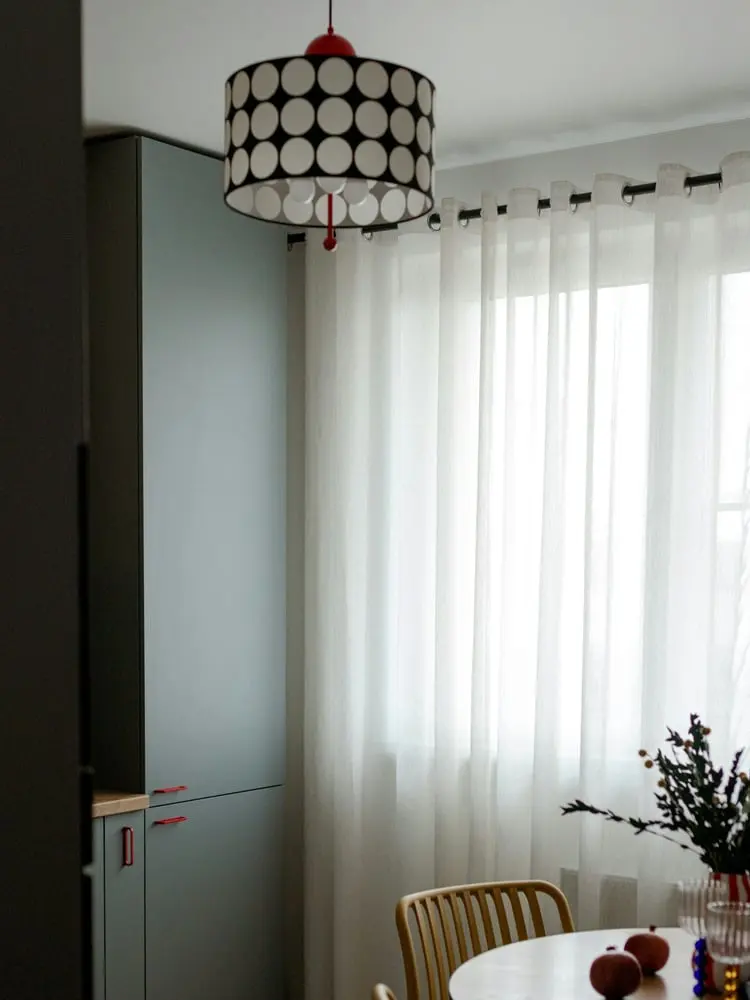 a modern kitchen with a patterned lampshade and sheer curtains