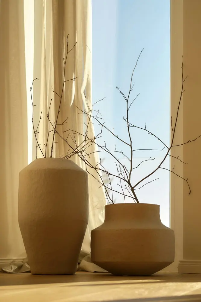 two textured vases with bare branches by window