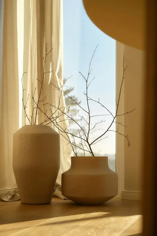 two textured vases with dry branches near window