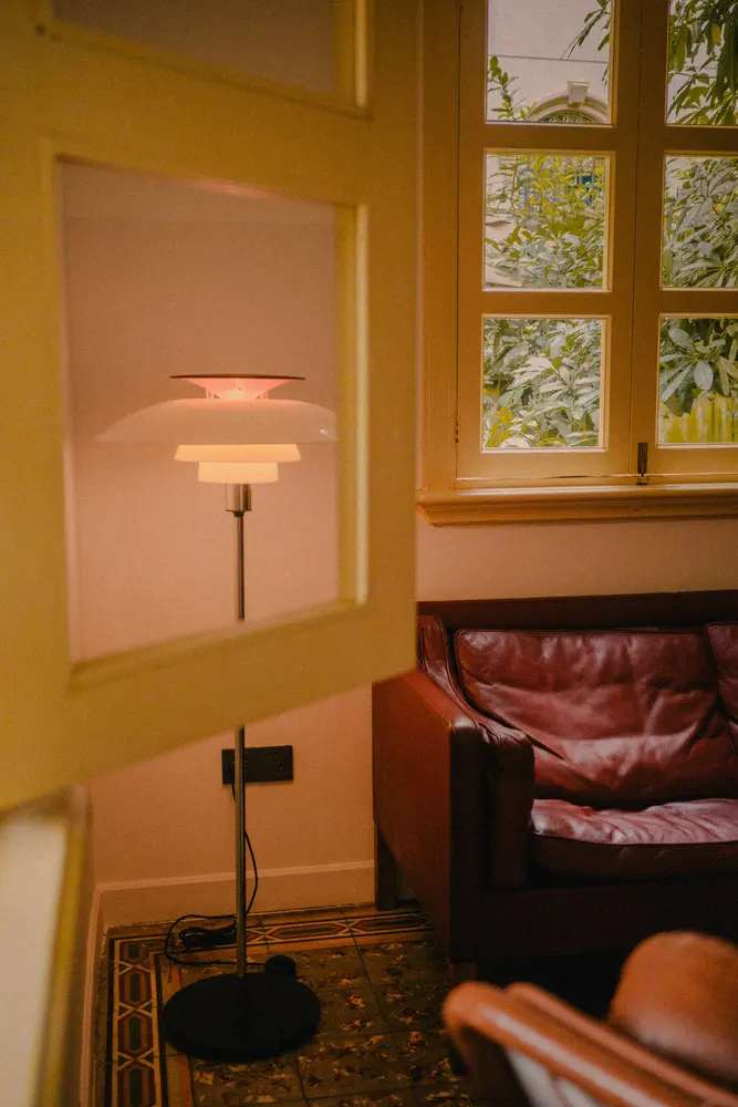 a modern floor lamp next to a leather sofa