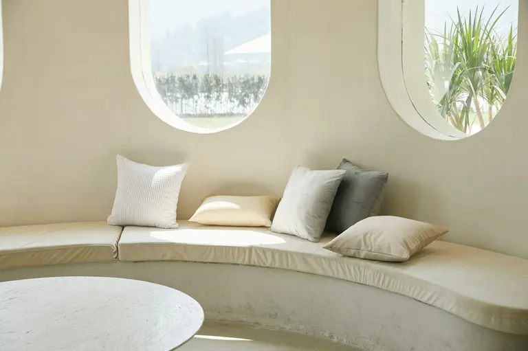 A white sofa beside a round wooden table in a bright room